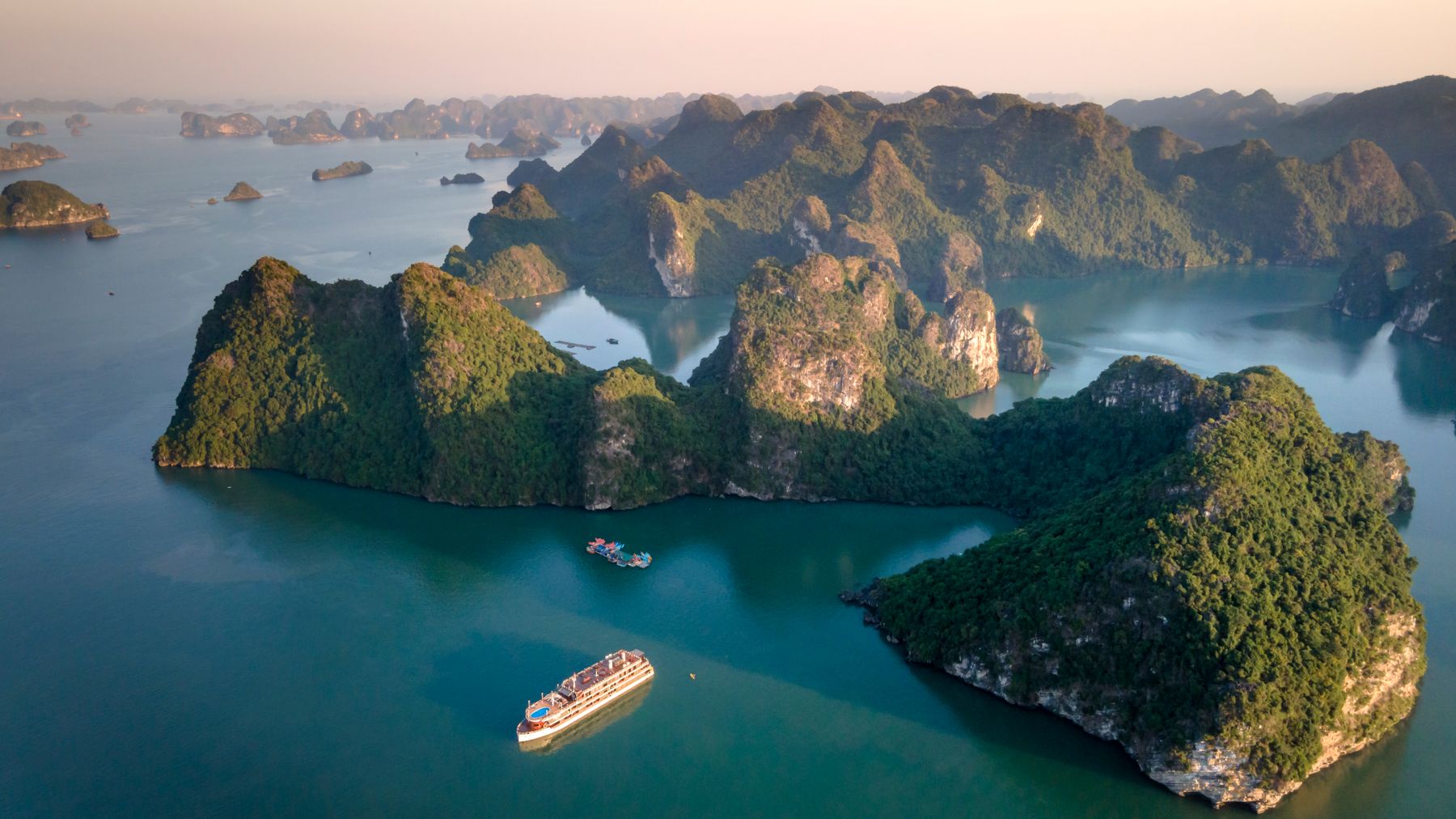 An aerial view showcasing the stunning limestone islands of Ha Long Bay at sunset.