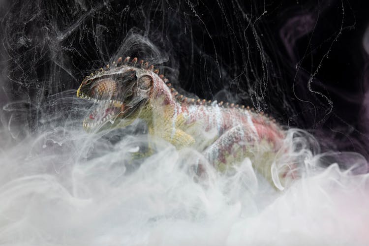 A Dinosaur Toy In A Cloud Of White Ink Underwater