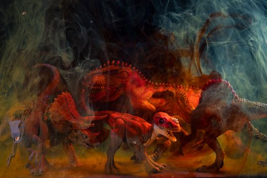 Vibrant dinosaur toy figures enveloped in colored smoke create a dramatic still life composition.