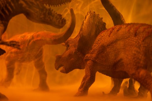 Close-up of toy dinosaurs in a smoky orange setting, creating a dramatic prehistoric scene.