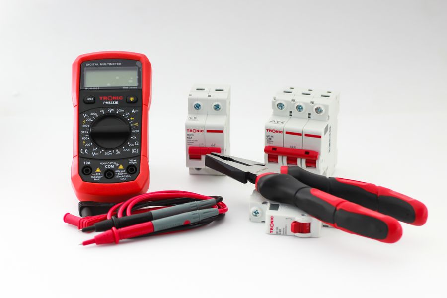 Elektrowerkzeuge, Messgerät und Sicherungsautomaten auf heller Arbeitsfläche