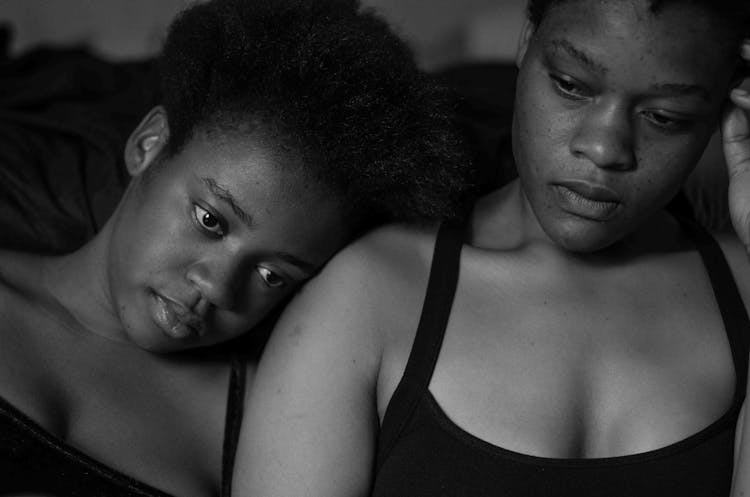 A Child Leaning Her Head On Her Mother's Shoulder