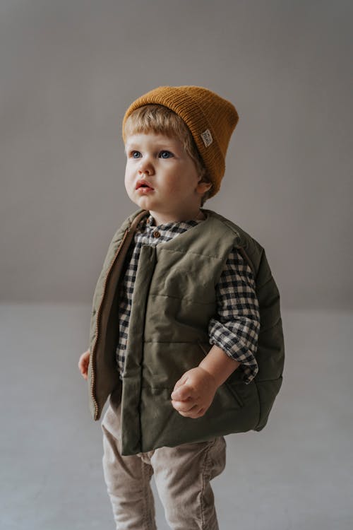 An Adorable Toddler with Brown Knit Cap and Grey Vest · Free Stock Photo