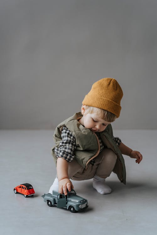 A Toddler with Brown Knit Cap Playing with a Toy Truck