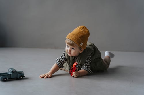 A Good Looking Toddles Crawling on the Floor with a Toy  Car