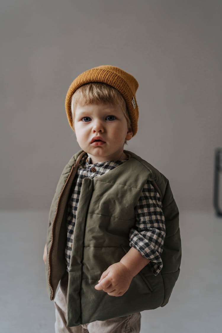 A Little Boy In A Vest And A Beanie