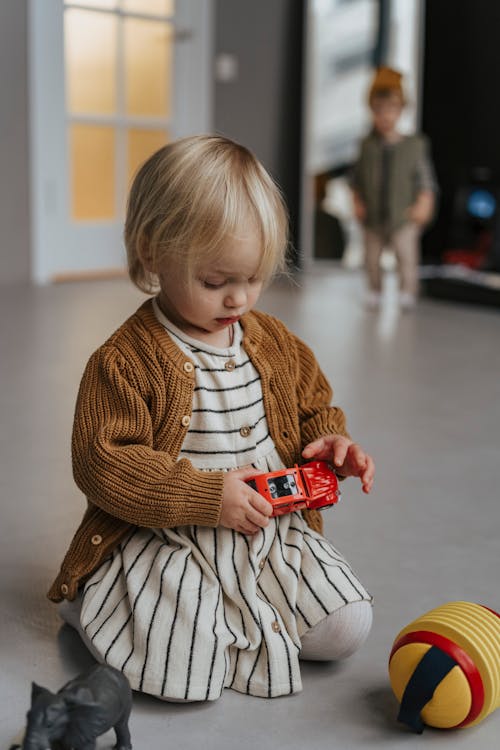 A Pretty Toddler Holding a Red Toy Car