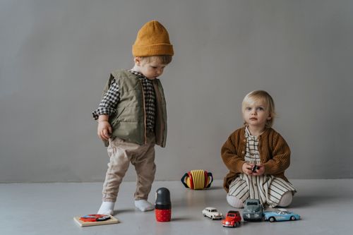 Free Two fashionable children play with toy cars in an indoor setting, showcasing autumn fashion. Stock Photo