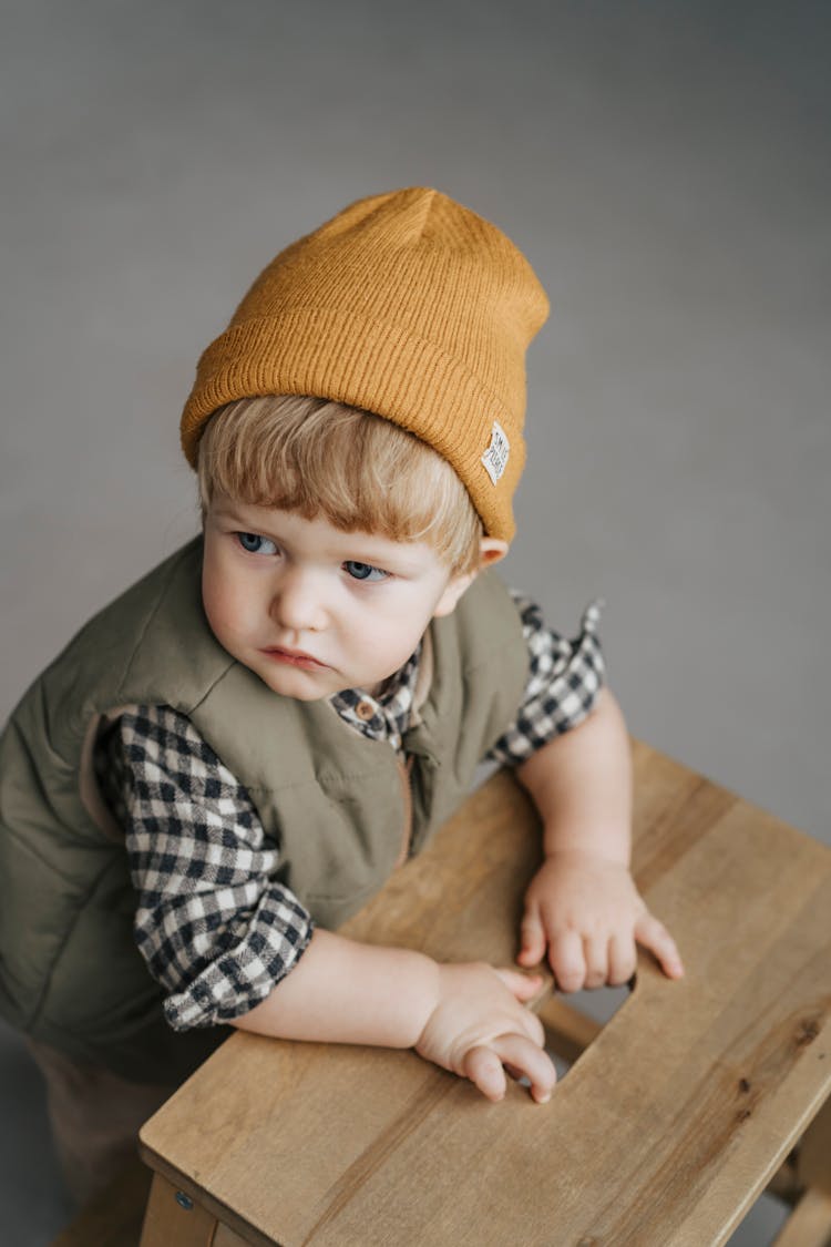 A Little Boy In A Vest And A Beanie