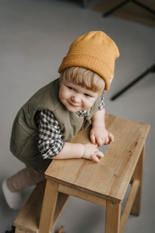 Free Cute toddler wearing a knit cap and plaid shirt climbing a wooden ladder indoors. Stock Photo
