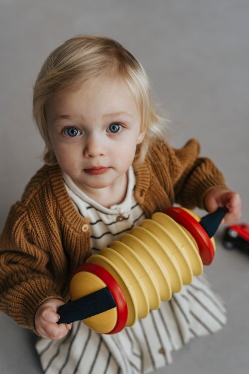 Free Adorable child with bright blue eyes holding a toy, captured indoors. Stock Photo