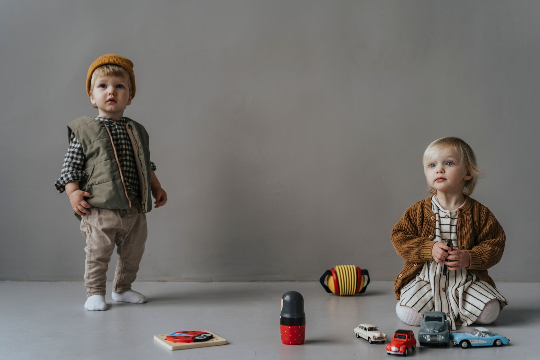 Toddlers wearing cozy everyday outfits in a soft bright studio room