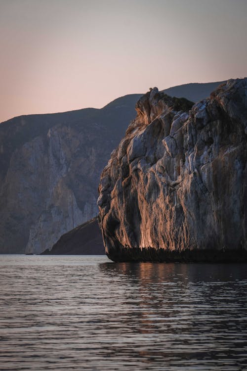Rocky cliffs surrounding rippling sea at sunset
