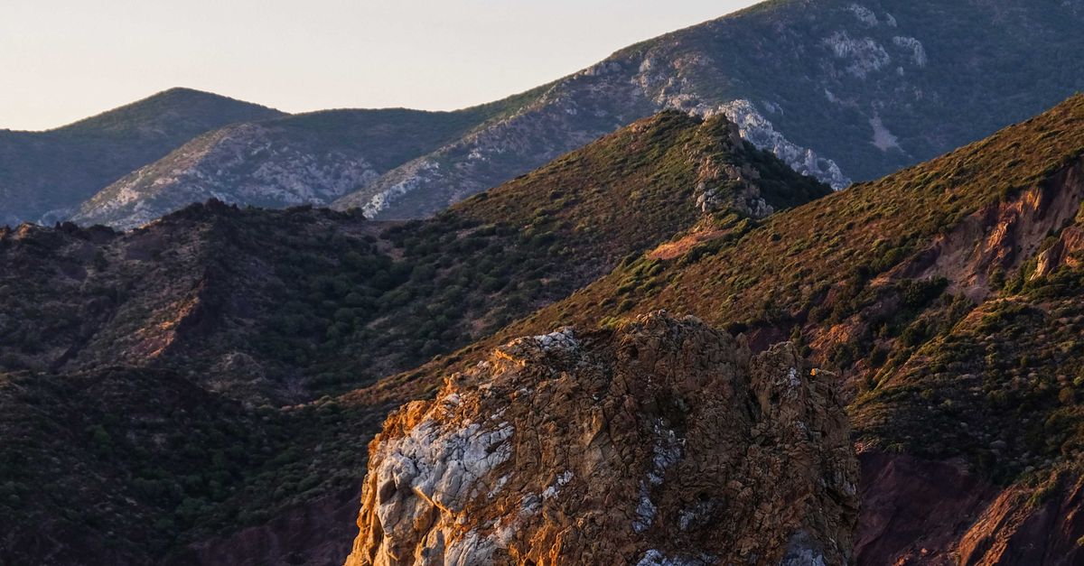 Swashed Cliff Rocky cliff washed by rippling lake in highland · Free Stock Photo