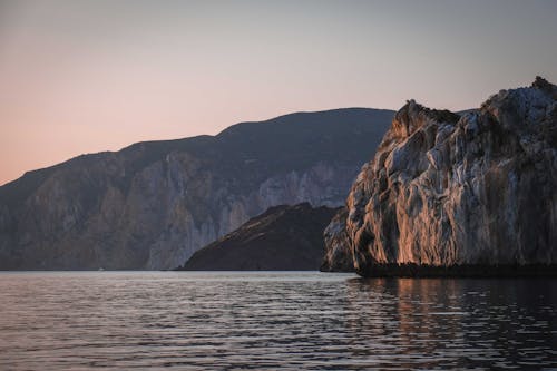 Rocky mountains near rippling sea at sundown