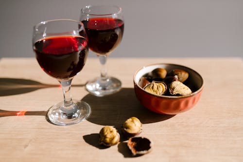 Wine Glasses with Brown Liquid Near a Bowl of Chestnuts