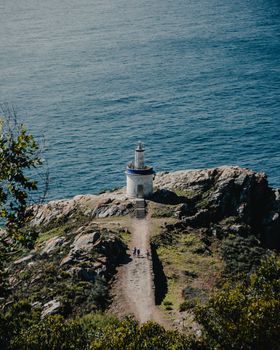 Scenic view of a lighthouse on a rocky coastline in Galicia, Spain with the ocean in the background.