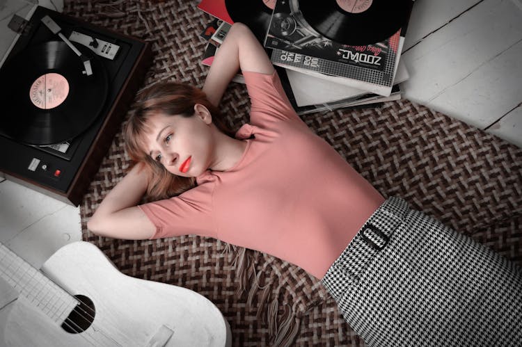 Dreamy Woman Lying On Floor Near Vinyl Record Player