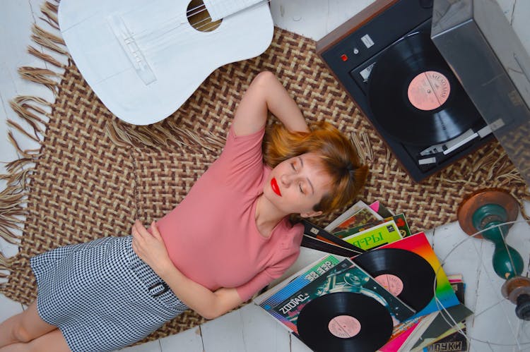 Relaxed Woman Lying On Floor And Listening To Vinyl Player