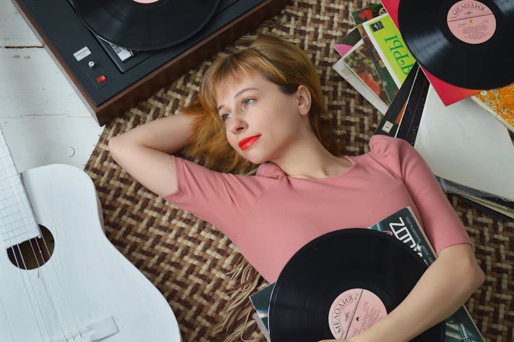 Relaxed Woman Listening To Vinyl Player And Lying On Floor