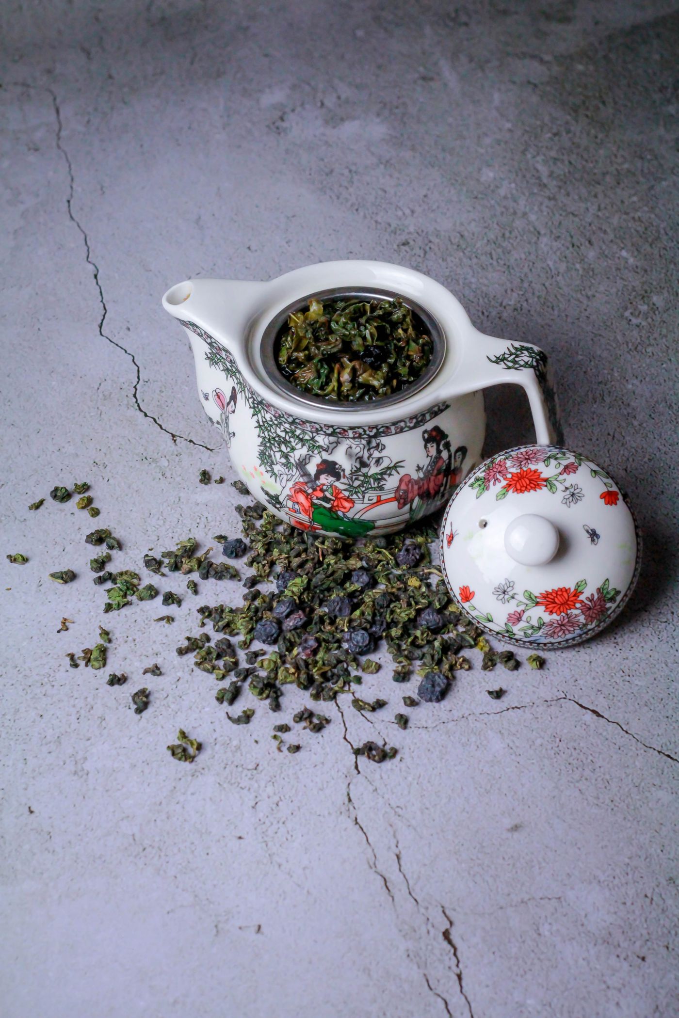 Loose oolong tea beside a ceramic teapot.