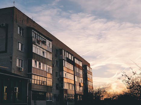 A city apartment building with moody sky at sunset, highlighting urban life.