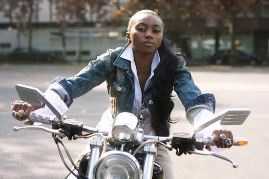 A confident woman poses on a motorcycle outdoors, embodying freedom and style.