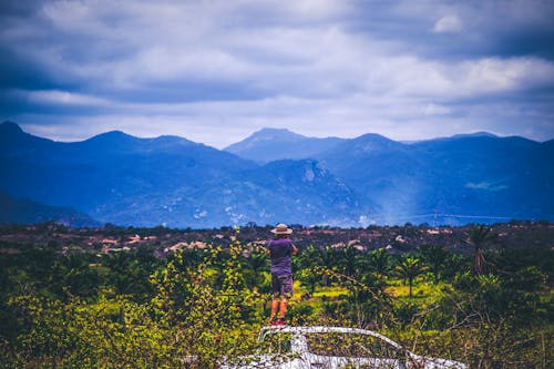 Persona Che Indossa Cappello Da Sole Guardando Le Montagne Sotto Il Cielo Nuvoloso