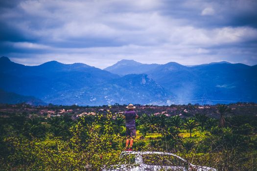 一名男子在阴天开车，拍摄风景优美的山景