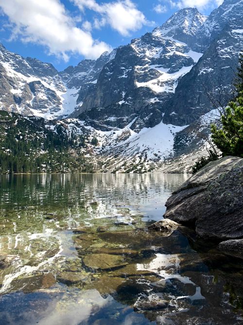 Free A picturesque alpine lake in the Tatra Mountains, showcasing serene nature with snow-capped peaks. Stock Photo