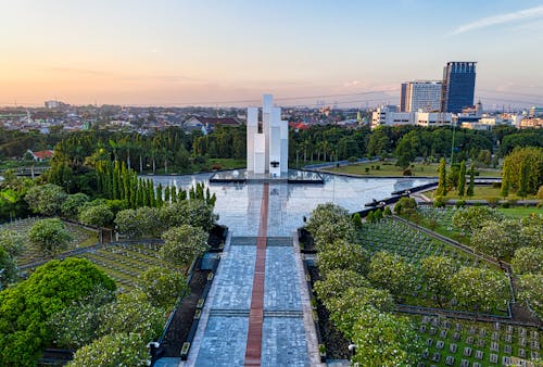 Narrow paved walkway leading to modern building located on national main heroes cemetery with tombstones and lush green trees in Kalibata