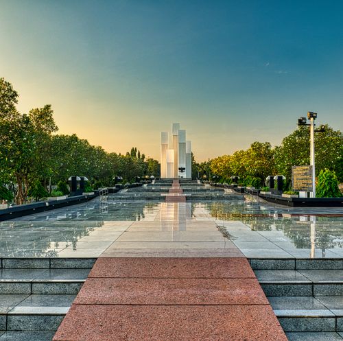 Free Granite pathway with steps among lush green trees leading to modern tall building in national main heroes cemetery in Kalibata Stock Photo