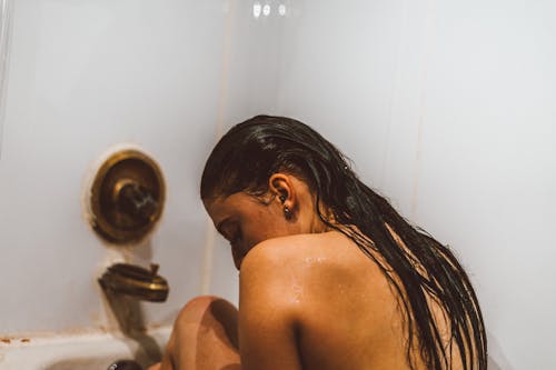 A Woman Sitting in the Bathtub in the Bathroom