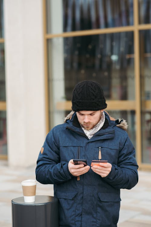 Serious man using smartphone while making online purchase with credit card