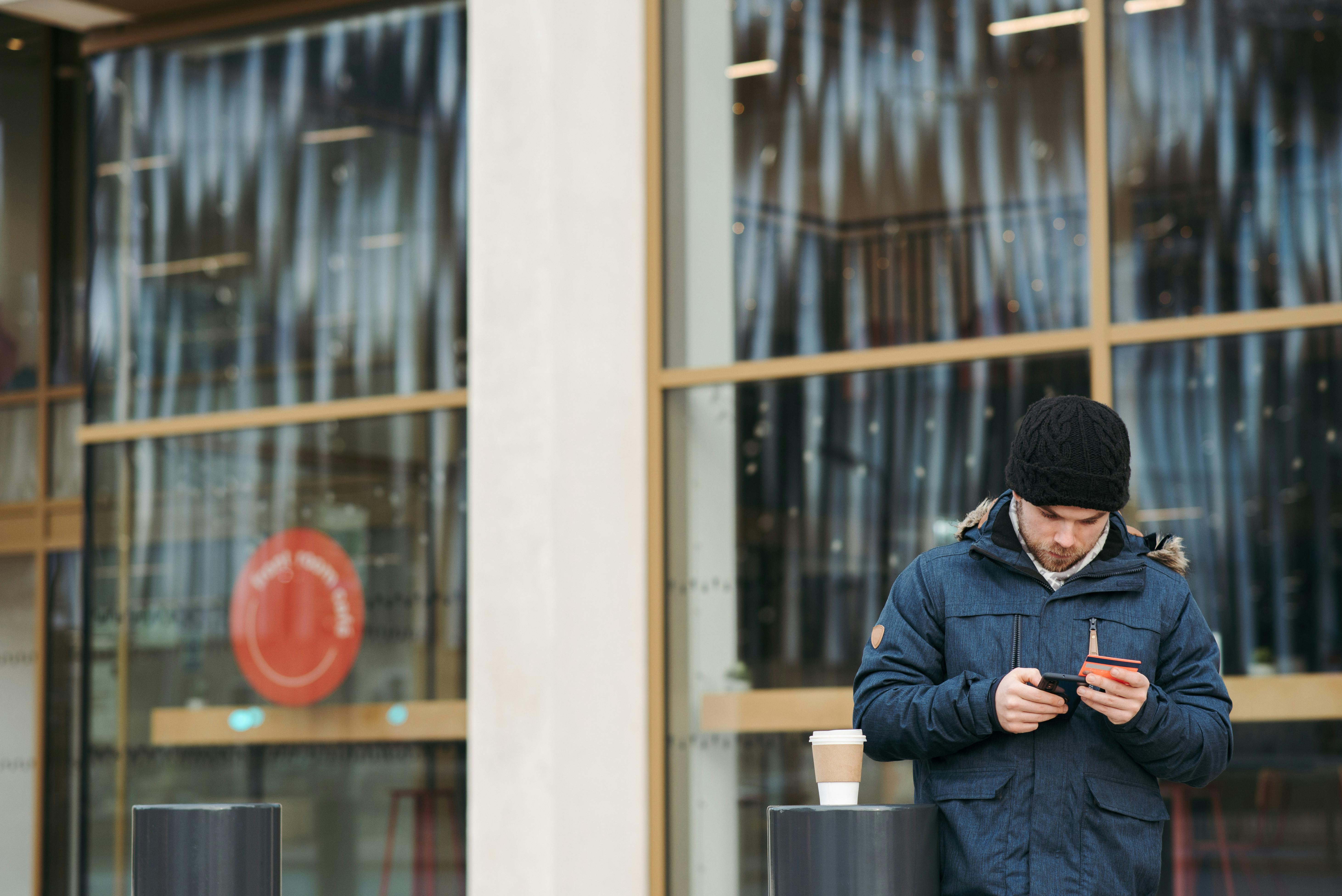 serious guy entering credit card details while making payment with smartphone on street