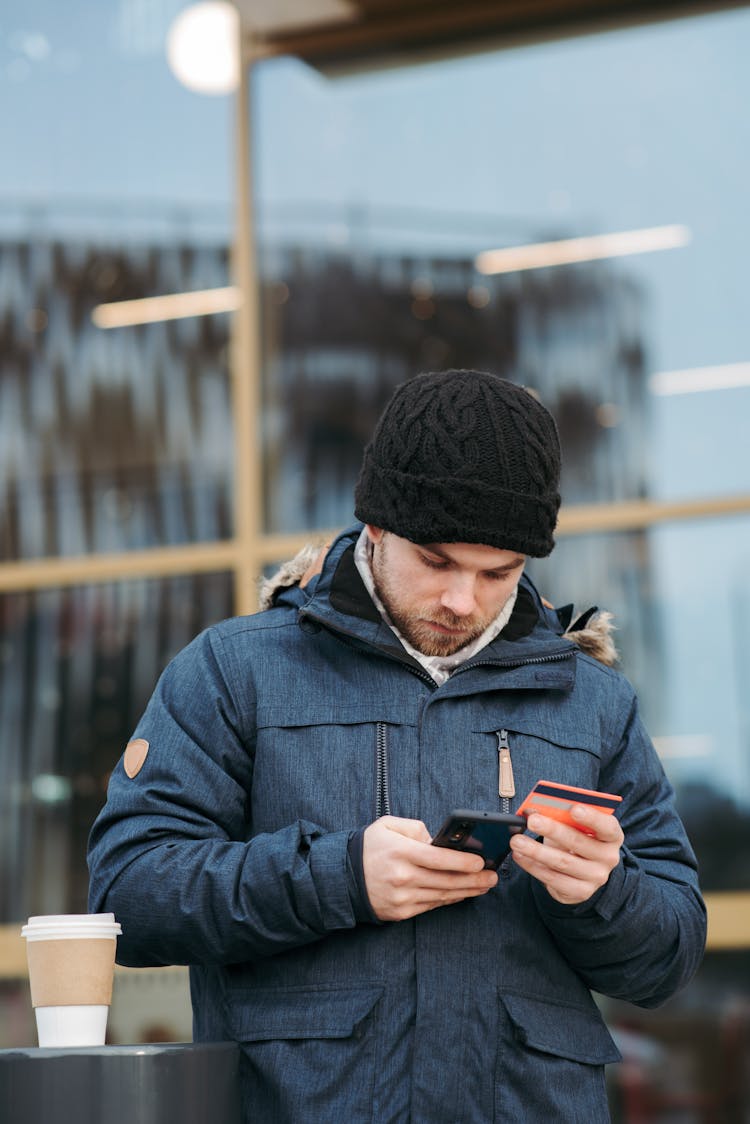 Serious Man Using Plastic Card While Making Online Shopping On Smartphone On Street