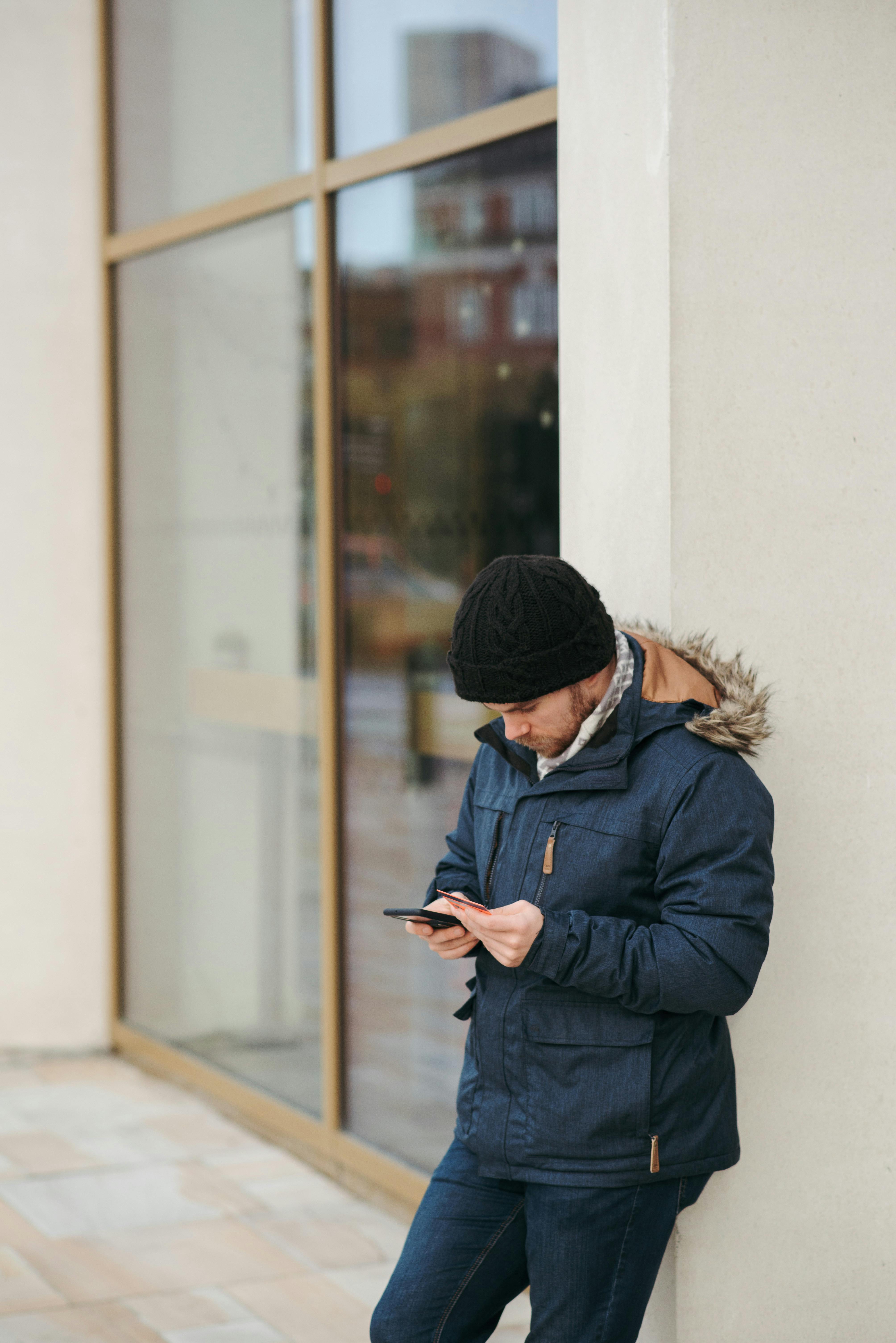 thoughtful man browsing smartphone on street in daylight