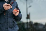 Male taking photo of credit card on smartphone on street in daytime