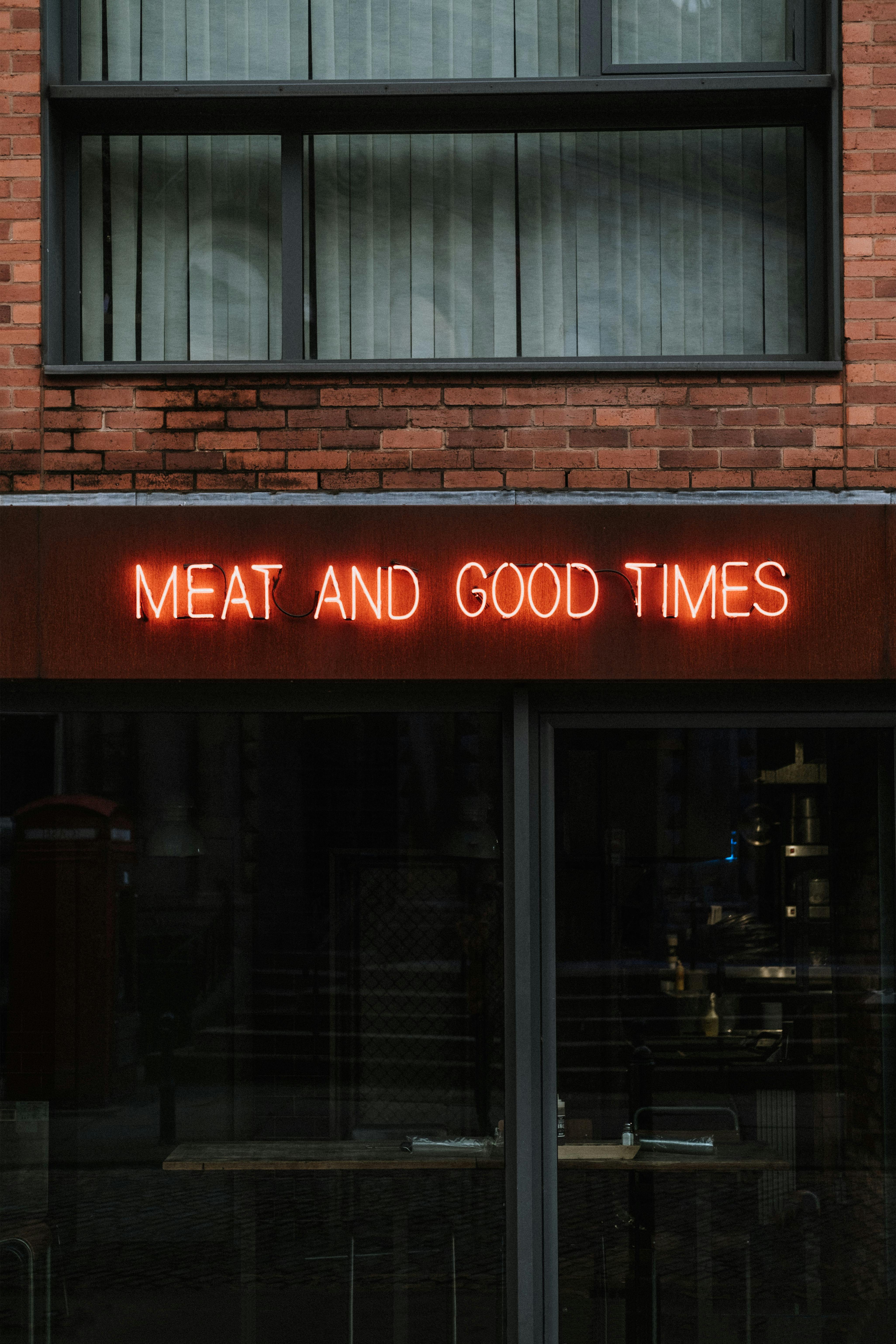 facade of cafe with bright signboard above glass wall