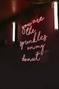 Red neon signboard with inscription hanging on wall in dark public place at night