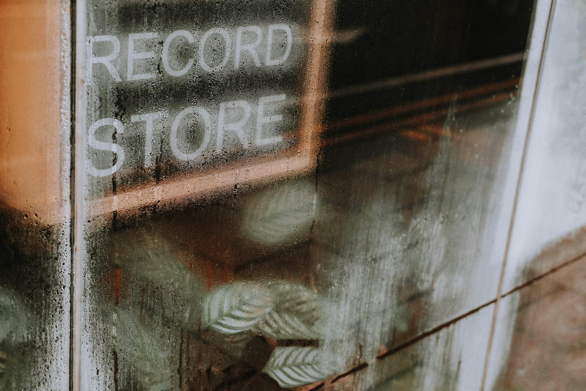 High angle of transparent glass wall with wet surface covered with water drops of record store