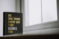 Rectangular shaped book with printed title on black hardcover on windowsill in house in daytime
