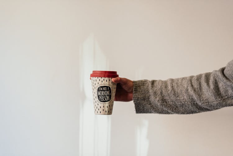 Faceless Person Showing Coffee To Go On Light Background