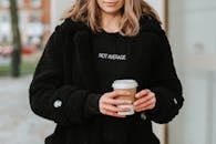 Crop smiling woman with coffee to go on city street