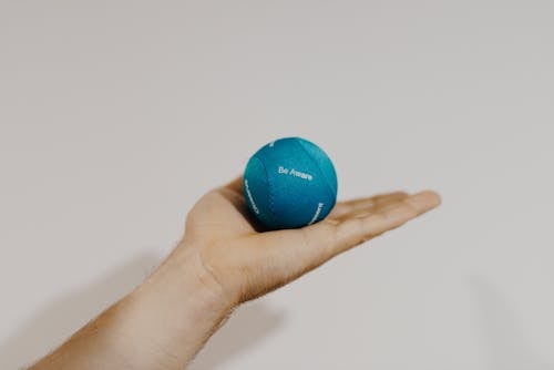 Crop sportsman showing therapy ball on light background