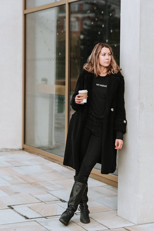 Melancholic woman with takeaway coffee on city street