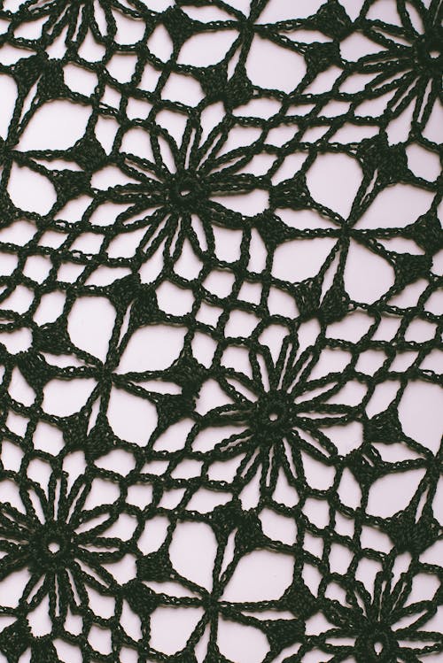 Textured background of knitted floral ornament with holes