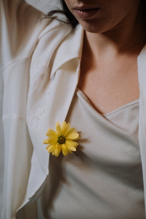 그녀의 목에 노란색 꽃과 흰색 V 넥 셔츠에 여자