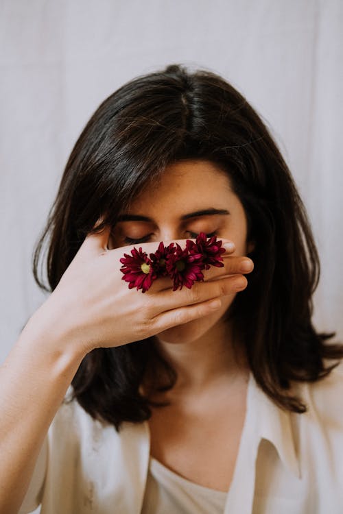 Free Peaceful woman with closed eyes covering face with hand decorated with blossoming flowers Stock Photo