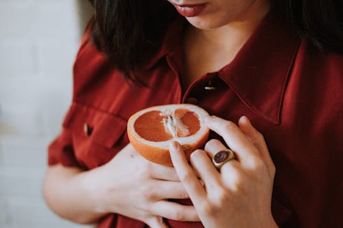 Vrouw Die In Rood Overhemd Gesneden Oranje Fruit Houdt